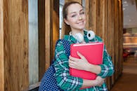 Smiling student holding book and wearing headphones, ready for study.